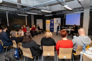 Na zdjęciu widać uczestników siedzących w półokręgu i prowadzących warsztaty: Katarzynę Głuch-Juszkiewicz oraz Jarosława Juszkiewicza