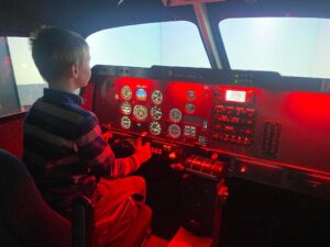 Chłopiec steruje samolotem w symulatorze lotu