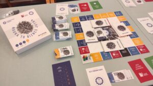 Zdjęcie przedstawia planszówkę z plami dookoła planszy oraz dużą ilością kart do gry po bokach
