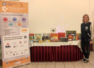 Zdjęcie przedstawia stanowisko promocyjne z planszówkami