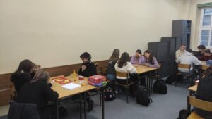 Zdjęcie przedstawia kilka osób siedzących przy dwóch stołach grających w gry planszowe