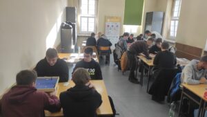 Zdjęcie przedstawia dużą ilość osób siedzących przy ławkach oraz grających w gry planszowe