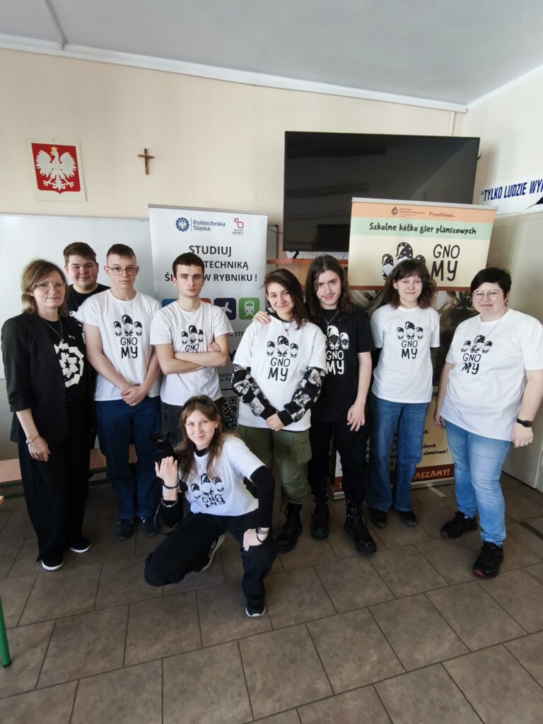 Organizatorzy spotkania pozują do wspólnego zdjęcia na tle banerów promocyjnych. Kliknięcie powoduje zwiększenie zdjęcia.