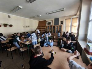 Dzieci siedzą przy stołach i grają w różne gry planszowe. Kliknięcie powoduje zwiększenie zdjęcia.
