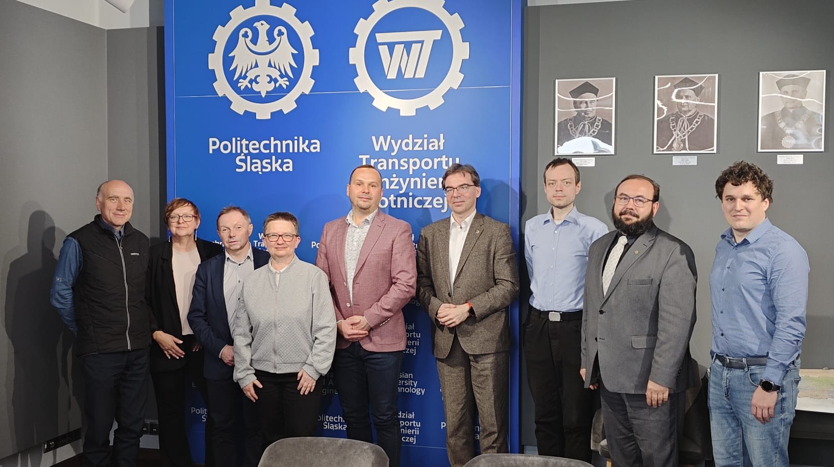 uczestnicy spotkania na tle ścianki wydziałowej