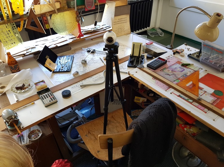 Na zdjęciu widzimy dawny warsztat pracy studenta architektury. Jest to stół do projektowania. Starte kalkulatory, ekierki, linijki, lampy