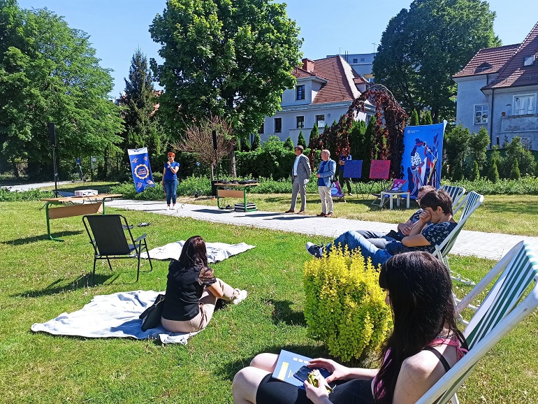 Na zdjęciu wadzimy kampus Politechniki Śląskiej. Na pierwszym planie na trawie siedzą ludzie na leżakach i kocach na drugim planie stoją dyrektor CPN dr hab. Aleksandra Ziembińska-Buczyńska, prof. PŚ, oraz prorektor ds. infrastruktury i promocji dr hab. inż. Tomasz Trawiński, prof. PŚ, a także dr inż. Marcin Górski, Dyrektor Centrum Zarządzania Projektami.