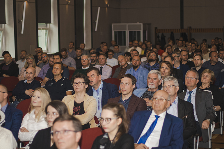 Zdjęcie przedstawia siedzących ludzi na auli.