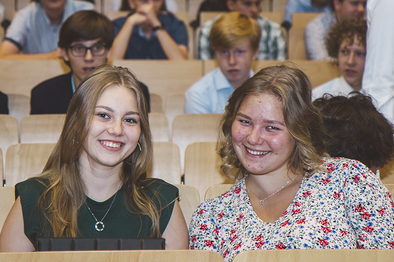 Zdjęcie przedstawia dwie młode uśmiechające się do obiektywu uczennice liceum.
