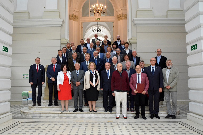 Na zdjęciu widzimy członków zgromadzenia stojących i pozujących do zdjęcia przed budynkiem
