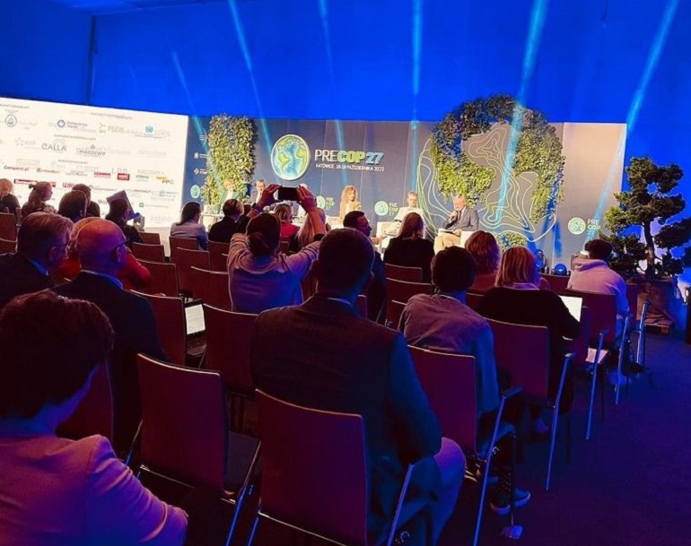 Na zdjęciu widzimy salę konferencyjną w Międzynarodowym Centrum Kongresowym w Katowicach. Na pierwszym planie widzimy siedzących tyłem uczestników przed nimi scena z prelegentami