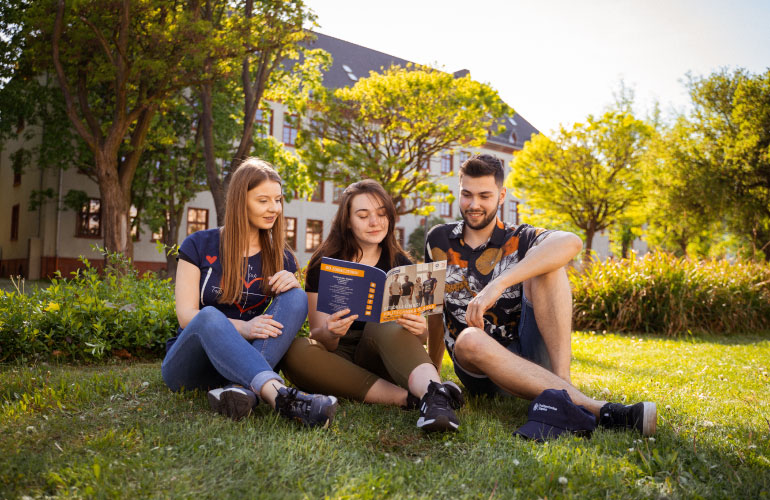 grupa studentów siedzących na trawie