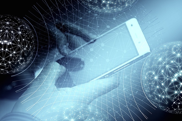 Na zdjęciu widzimy dłonie trzymające telefon komórkowy w tle niebieskie linie, niektóre układające się w globus.