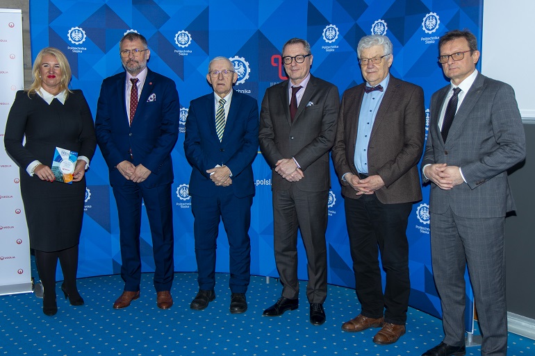 Na zdjęciu widzimy uczestników konferencji prasowej stojących na tle ścinki Politechniki Śląskiej