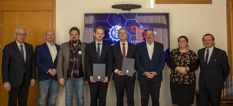 Na zdjęciu widzimy uczestników podpisania umowy stojących na tle ścianki Politechniki Śląskiej