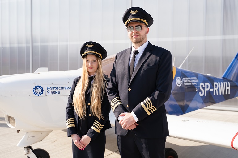Na zdjęciu widzimy dwóch pilotów kobietę i mężczyznę na tle małego samolotu