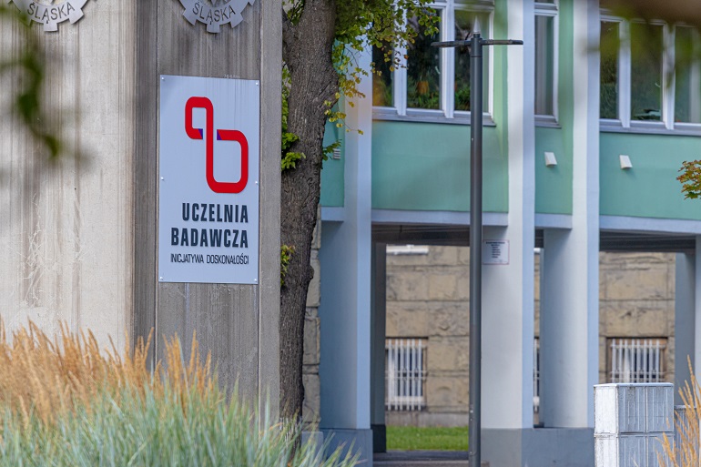 Na zdjęciu widzimy budynek kampusu uczelni a przed nim totem z napisem uczelnia badawcza