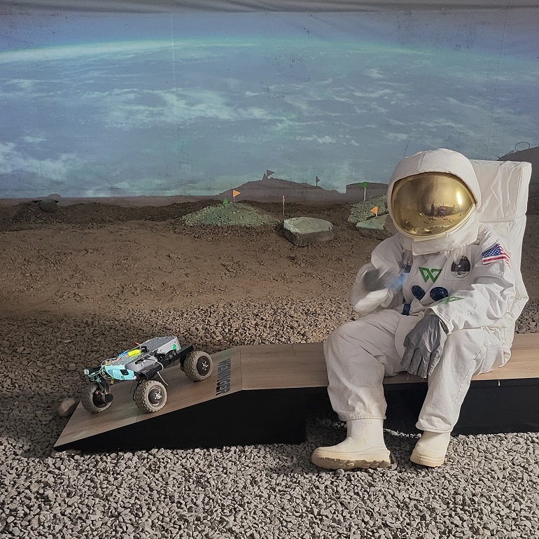 Na zdjęciu widzimy kosmonautę obok niego mały łazik