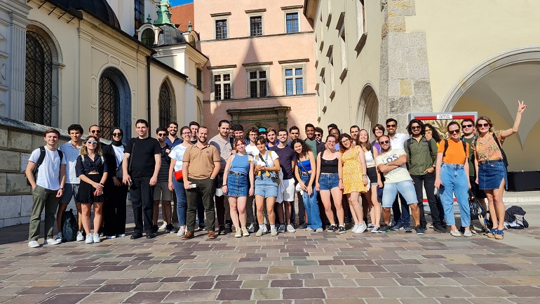 Na zdjęciu widzimy studentów podczas wycieczki stojących w grupie na tle zamku