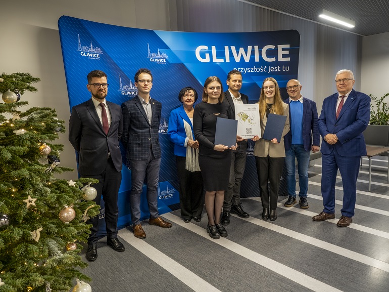 na zdjęciu widzimy laureatów konkursu oraz przedstawicieli UM Gliwice.. Wszyscy stoją na tle ścianki niebieskiej z napisem Gliwice