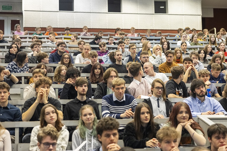 na zdjęciu aula i siedząca w niej młodzież