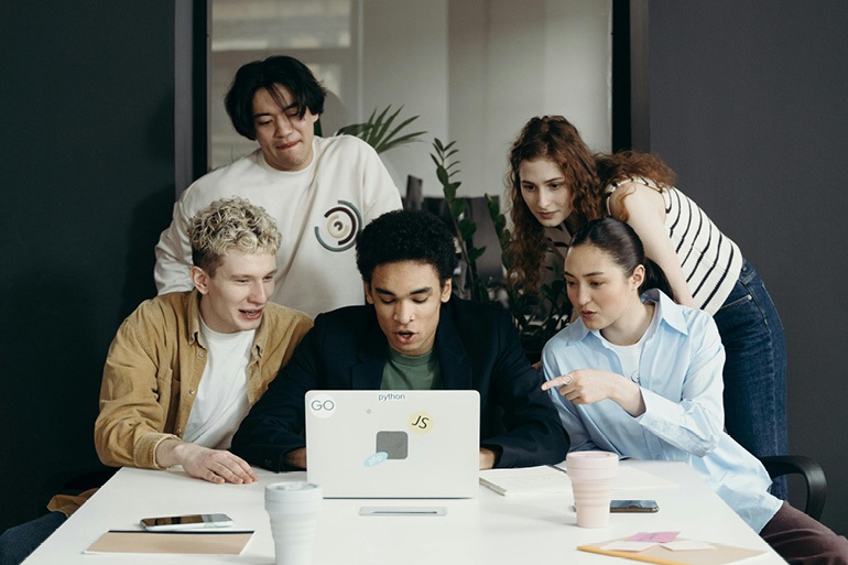 na zdjęciu kilkoro studentów przy laptopie