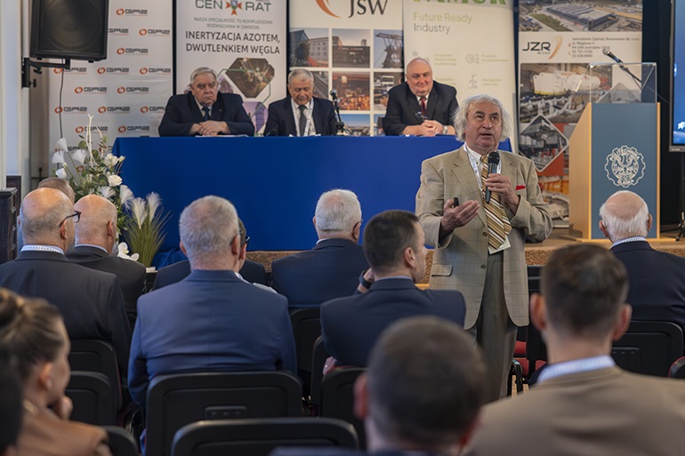 na zdjęciu widzimy od tyłu siedzących na sali konferencyjne uczestników i prelegenta mówiącego do mikrofonu