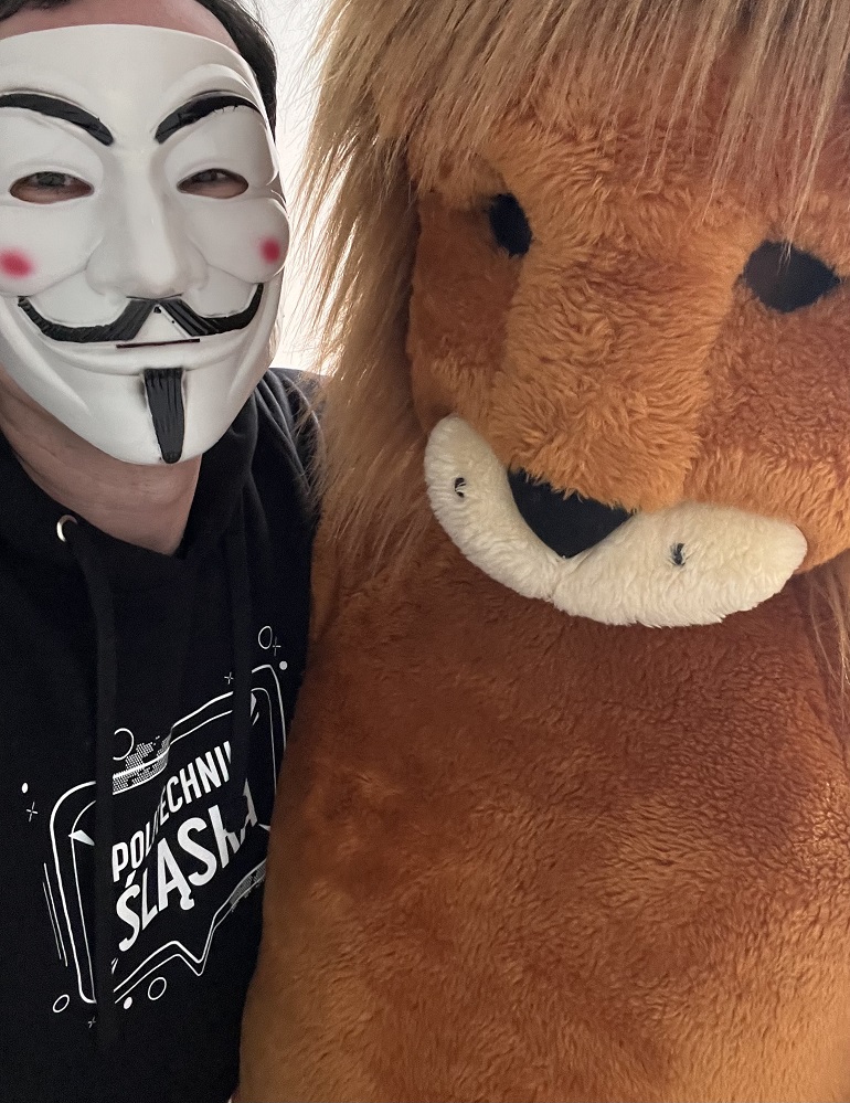 na zdjęciu naukowiec w masce oraz pluszowy lew
