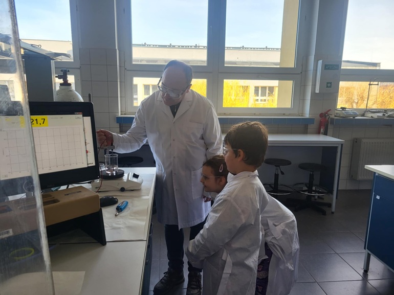 Na zdjęciu laboratorium dwójka dzieci i naukowiec