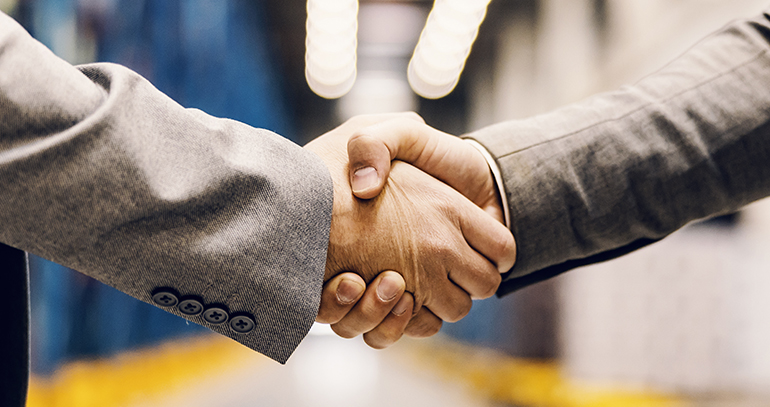 Close up of a business partners shaking hands at warehouse.