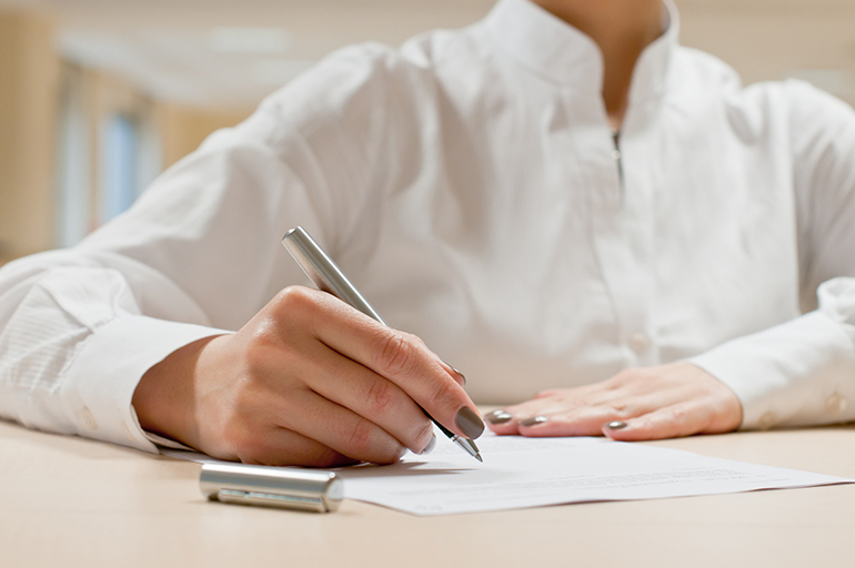 business woman is writing a document at her office, selective focus on hand
