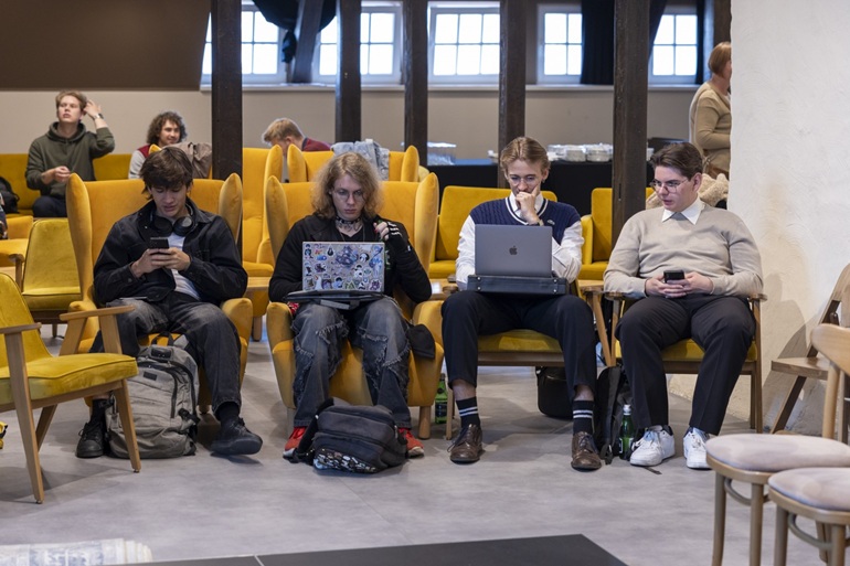 na zdjęciu grupa uczniów przy laptopach