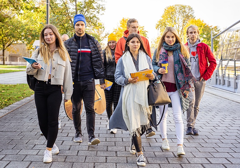 na zdjęciu grupa studentów idąca przez kampus